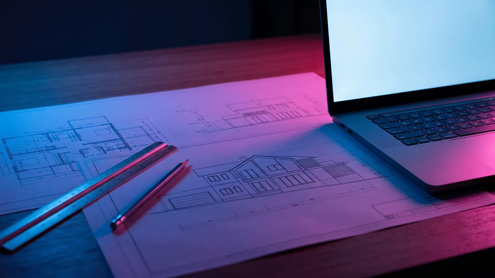 Des plans d'architecte étalés sur un bureau dans la pénombre, une règle métallique et un crayon posés dessus, un ordinateur portable à l'écran bleuté à côté, la scène éclairée de bleu profond et de magenta.